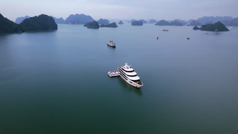 Antena-De-Cruceros-Anclados-En-La-Bahía-De-Ha-Long,-Vietnam,-Que-Transportan-Turistas-En-Aguas-Tropicales