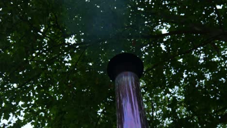 Looking-Up-At-Metallic-Flue-With-Steam-And-Heat-Being-Expelled-Under-Forest-Canopy