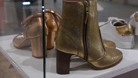 Shining-golden-shoes-are-behind-a-glass-in-a-fashion-museum,-expensive-masterpiece