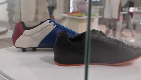 Two-sneakers-behind-a-glass-in-a-museum,-black-and-French-Colors-shoes