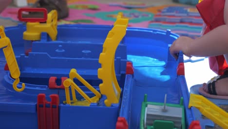 Blick-Auf-Ein-Kind,-Das-Mit-Einem-Wasserspielzeug-Spielt,-An-Dem-Kleine-Plastikboote-Vorbeischwimmen