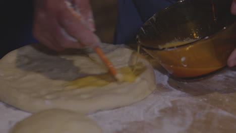Close-up-shot-of-a-cook-brushing-traditional-Meskhetian-bread-with-egg-wash