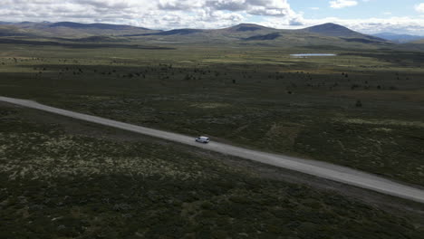 Drohne-Erfasst-Den-Van,-Der-Durch-Die-Endlose,-Isolierte-Straße-Fährt,-Und-Im-Hintergrund-Ist-Der-Rondane-nationalpark-Zu-Sehen