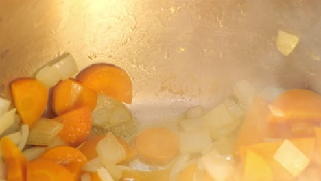 Nahaufnahme-Von-Gehackten-Karotten-Und-Zwiebeln,-Die-Im-Topf-Mit-Aufsteigendem-Dampf-Köcheln