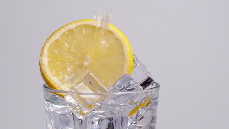 Kaltes,-Frisches-Sprudelwasser,-Das-Mit-Eis-Und-Zitronenscheiben-In-Ein-Glas-Gegossen-Wird