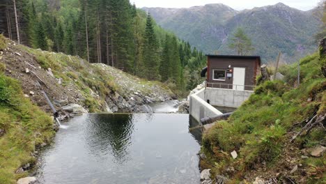 Static-aerial-above-mountain-river-intake-dam-to-Markaani-hydroelectric-powerplant-in-Norway---Looking-towards-small-dam-and-house-with-valves-and-flow-control---Owned-by-captiva-asset-management