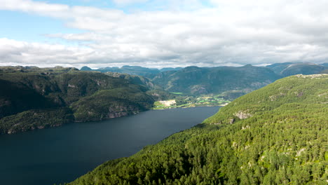 reverse-hyper-lapse-away-from-fjord-over-forested-mountain-in-shadow-of-clouds