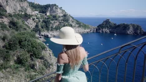 Bella-Mujer-Bajando-Las-Escaleras-Con-Vistas-Al-Paisaje-Marino-Mediterráneo-Y-Acantilados-Rocosos-En-Conca-Dei-Marini,-Costa-De-Amalfi,-Italia