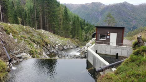 Small-dam-and-water-intake-for-a-mini-hydroelectric-powerplant-called-Markaani-in-Vaksdal-Norway---Intake-high-up-in-the-mountains-with-valley-and-natural-mountain-background