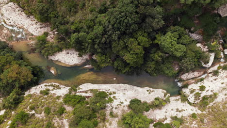 Drone-Ascendiendo-En-La-Corriente-Del-Río-En-La-Reserva-Natural-Cavagrande-Del-Cassibile-En-Siracusa,-Italia