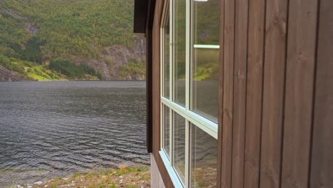 Kamera-Gleitet-Entlang-Der-Wand-Des-Wasserkraftwerks-Markaani-In-Norwegen,-Bevor-Sie-Ein-Warnschild-Enthüllt,-Das-über-Das-Kraftwerk-Informiert---Bolstadfjord-Meer-Im-Hintergrund