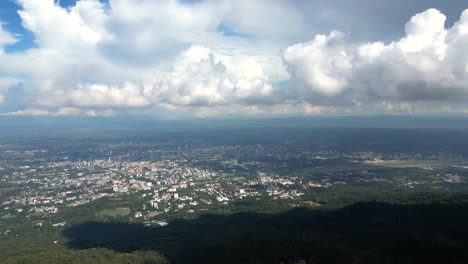Vista-Panorámica-Aérea-Rápida-A-Través-De-La-Jungla-Verde-Y-Chiang-Mai-En-La-Distancia