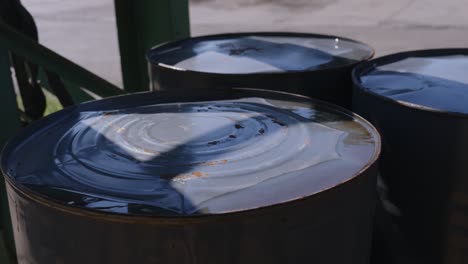 Ripples-of-oil-on-iron-barrels-stocked-at-a-open-warehouse