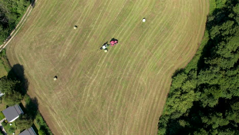 Aerial-Birds-Eye-View-Of-Tractor-Pulling-Trailed-Across-Green-Field-In-Chmielno