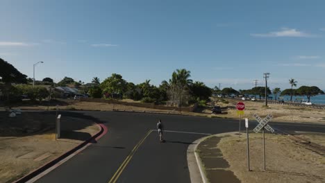 Man-electric-skateboarding-in-a-residential-area-using-a-drone-Auto-fly-feature-to-record-his-movements-on-"follow-me"-mode
