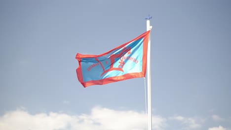 Bandera-De-Spetses-Con-Un-Ancla-Tradicional,-Un-Pájaro-Y-Una-Cruz-Ondeando-Al-Viento-Y-Otro-Pequeño-Azul-Cristiano-Azul