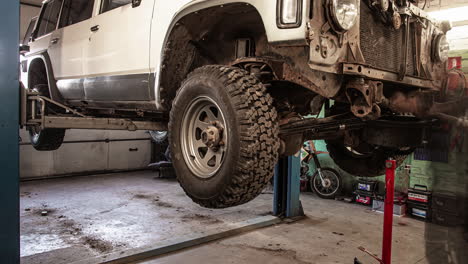 Auto-repair-shop,-Professional-mechanic-working-on-Off-road-vehicle-in-lifting-machine-at-the-garage,-Time-Lapse