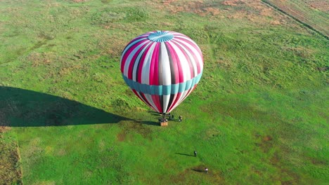 Aerial-view-of-hot-air-ballon-ready-to-take-off-from-a-green-field