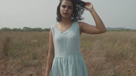 Shot-of-a-woman-in-a-blue-dress-moving-her-hair-with-her-hand-in-a-wide-field