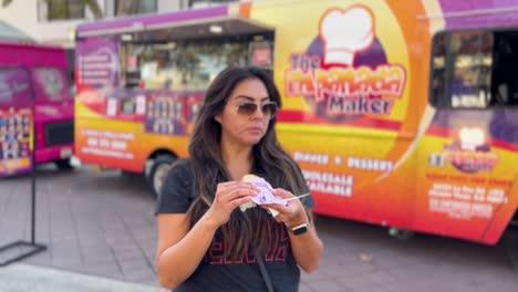 Attractive-Latina-female-eating-a-snack-purchased-from-a-food-truck