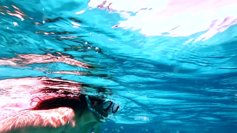 Woman-swimming-with-fish-in-blue-clear-water,-Zanzibar