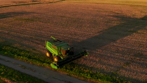 agriculture-machine-driving-through-field,-road-in-evening,-sunset,-visible-off-road-roads,-crop-fields,-horizon