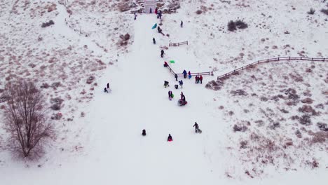 Aerial-of-a-kid-sledding-down-a-snowy-hill-at-a-fast-speed