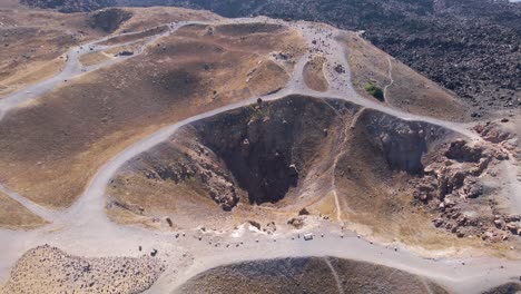 Aerial-view,-approaching-and-tilting-down-over-volcano-crater-at-Santorini-island,-Greece-in-slow-motion