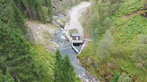 Aerial-approaching-small-intake-dam-to-river-powerplant-in-Norway-mountains-during-dry-period-with-low-water-level---Markaani-Norway-Vaksdal
