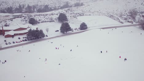 Wide-aerial-shot-of-kids-playing-in-a-large-field-of-snow-in-America
