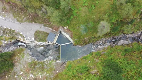 Top-down-aerial-view-of-small-intake-dam-to-hydroelectric-river-powerplant-during-drought-and-low-water-level---Birdseye-looking-down-and-slowly-moving-right---Markaani-Vaksdal-Norway