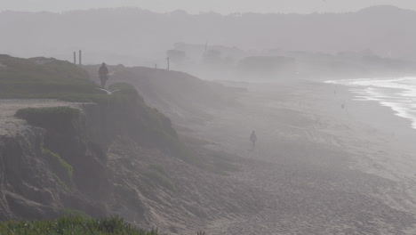 Slow-motion-panning-shot-of-a-foggy-day-at-Marina-State-Beach-Monterey-Bay-California-with-people