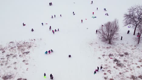 Drone-shot-of-kids-playing-on-a-steep-snowy-hill