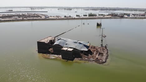 Drone-takes-an-anticlockwise-rotating-shot-of-the-isolated-broken-house-and-its-surrounding-field-which-submerged-by-water-because-of-flood-in-Pakistan