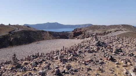 Bajo-Vuelo-Por-Rocas-Apiladas-Y-Sobre-El-Cráter-Del-Volcán-En-La-Isla-De-Santorini,-Grecia-En-Cámara-Lenta