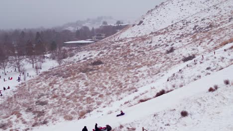 Tight-drone-shot-of-a-kid-sledding-down-a-snowy-hill-in-Boise,-Idaho