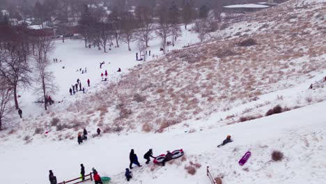 Aerial-shot-of-a-kid-sledding-down-the-side-of-a-hill-and-wiping-out