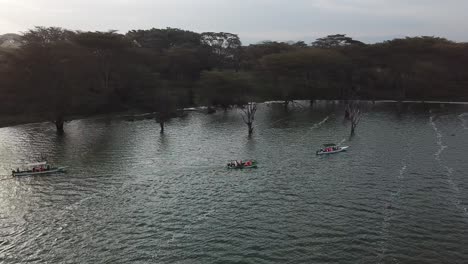 Orbital-drone-view-of-a-river-cruise-with-a-group-of-people-sailing-on-Lake-Naivasha,-Kenya