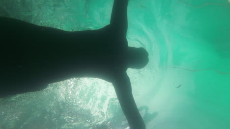 man-swimming-in-pool-under-coconut-tree-resort-hotel-under-water-shot-slow-motion