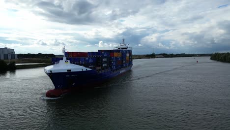 Orbit-shot-around-big-cargo-ship-with-stacked-naval-containers-sailing-on-river