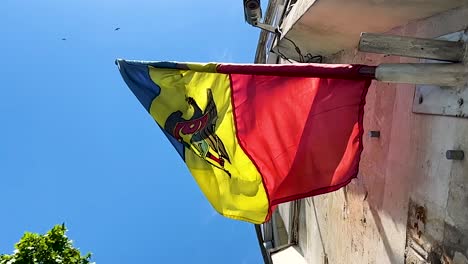 Flag-of-Moldova-on-facade-flagpole-blown-by-wind,-low-angle-shot