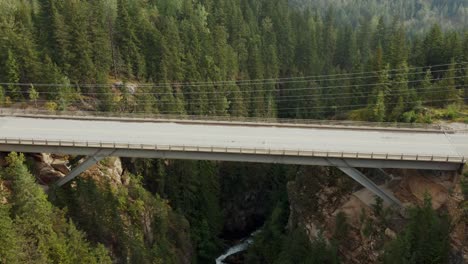 Slow-aerial-dolly-with-a-car-passing-over-the-canyon-bridge