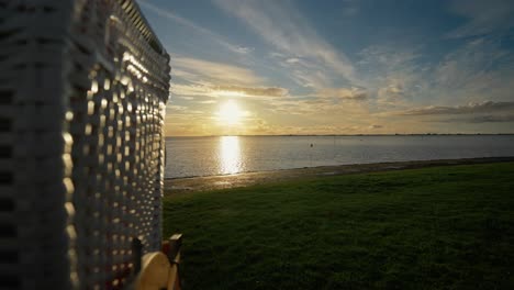 Golden-Sunset-Over-North-Sea,-Revealing-Strandkorb-Beach-Basket-Chair---dolly-back
