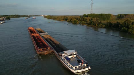 Aerial-view-of-cargo-ship-with-bulk-material-in-barges-slowly-moving-on-river