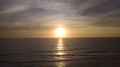 Sonnenuntergang-Meereslandschaft-Luftbild,-Bei-Sonnenuntergang-über-Die-Wasseroberfläche-Des-Ozeans-In-Richtung-Sonne-Fliegen,-Goldener-Bewölkter-Himmel,-Ruhige-Wellen-Und-Skyline-Am-Horizont