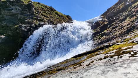 Idyllic-waterfall-in-Finnbuene-at-mountain-Vikafjell-during-sunny-spring-day---Static-clip-from-beautiful-Norwegian-mountain-nature---River-splashing-and-passing-close-to-camera---Static-handheld