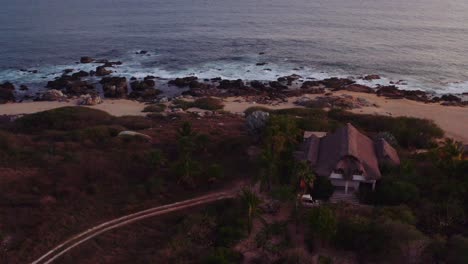 Slow-aerial-drone-moves-towards-oceanside-waterfront-luxury-villa-4k
