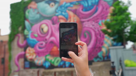 Woman-holding-iPhone-taking-a-photo-of-mural-in-the-city