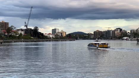 Thick-layer-of-ominous-clouds-sweeping-across-the-sky-with-Citycat-ferry-cruising-on-Brisbane-river-with-residential-buildings-along-the-river,-severe-weather-forecasted,-Brisbane-city,-Queensland