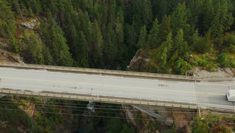 Aerial-shot-of-trucks-and-cars-passing-over-a-remote-canyon-bridge